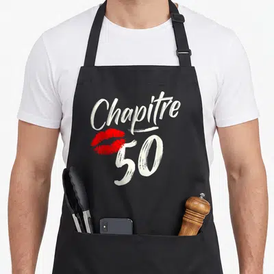 Tablier de cuisine noir avec inscription Chapitre 50 et trace de rouge à lèvres rouge.