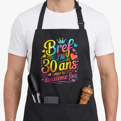 Tablier de cuisine noir avec inscription colorée Bref j'ai 30 ans pour la deuxième fois entourée de cœurs et d'une couronne.