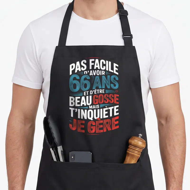 Tablier de cuisine noir avec typographie blanche bleue et rouge affichant un message d'anniversaire humoristique pour 66 ans.