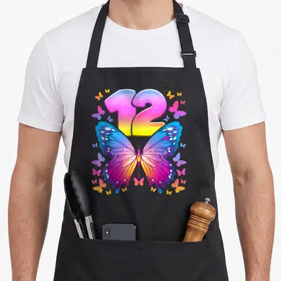 Tablier de cuisine noir avec un grand papillon multicolore et le chiffre 12 en gradient rose et jaune scintillant.