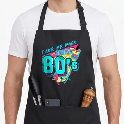 Tablier de cuisine noir avec illustration colorée Take Me Back to the 80's, cassette et patins à roulettes.