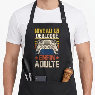 Tablier de cuisine noir avec manette de jeu vidéo et texte Niveau 18 Débloqué Enfin Adulte en style vintage.