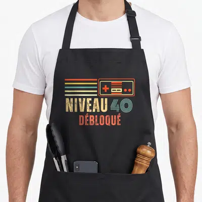 Tablier de cuisine noir avec illustration manette vintage et texte Niveau 40 Débloqué en couleurs rétro.