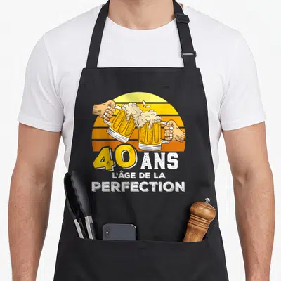 Tablier de cuisine noir avec illustration de bières et texte 40 ans l'âge de la perfection sur fond de soleil orange.