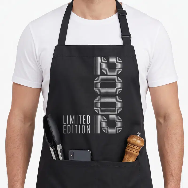 Tablier de cuisine noir avec le chiffre 2002 en lignes blanches verticales et Limited Edition en bas à gauche.