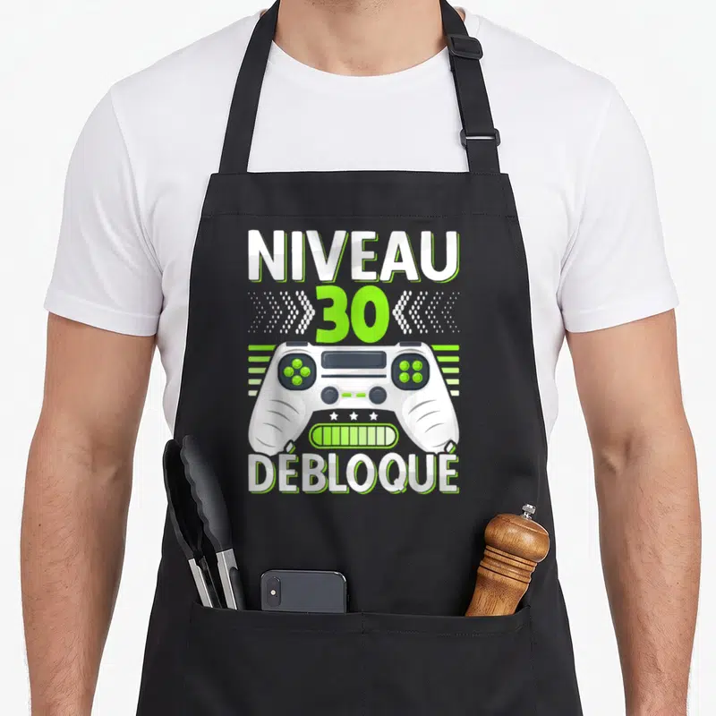 Tablier de cuisine noir avec illustration manette blanche et texte Niveau 30 Débloqué en vert lime et blanc.