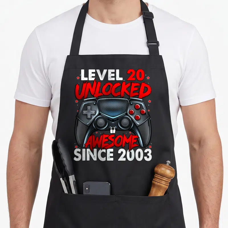 Tablier de cuisine noir avec illustration de manette de jeu vidéo et texte Niveau 20 Débloqué « Génial » Depuis 2003.