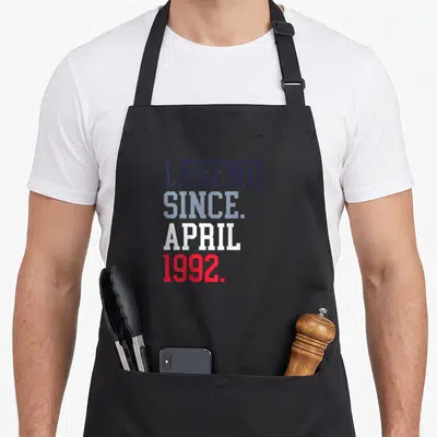 Tablier de cuisine noir avec inscription Legend Since April 1992 en lettres colorées.