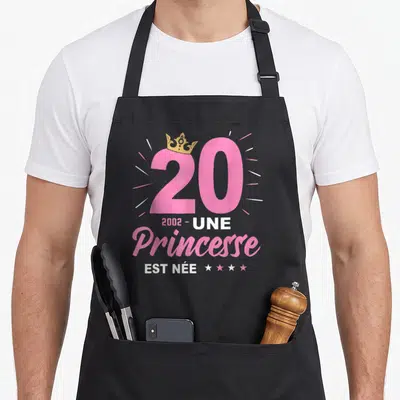 Tablier de cuisine noir avec inscription Une Princesse Est Née 2002 et couronne dorée sur le chiffre vingt.
