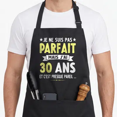 Tablier de cuisine noir avec le texte Je ne suis pas parfait mais j'ai 30 ans en typographie jaune et blanche.