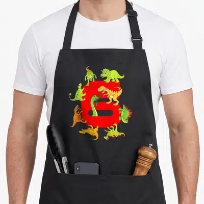Tablier de cuisine noir avec grand chiffre six rouge et plusieurs dinosaures colorés autour.