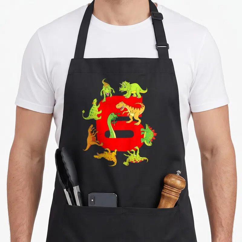 Tablier de cuisine noir avec grand chiffre six rouge et plusieurs dinosaures colorés autour.