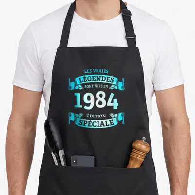 Tablier de cuisine noir avec inscription vintage Les légendes sont nées en 1984 Édition spéciale en bleu cyan et blanc.