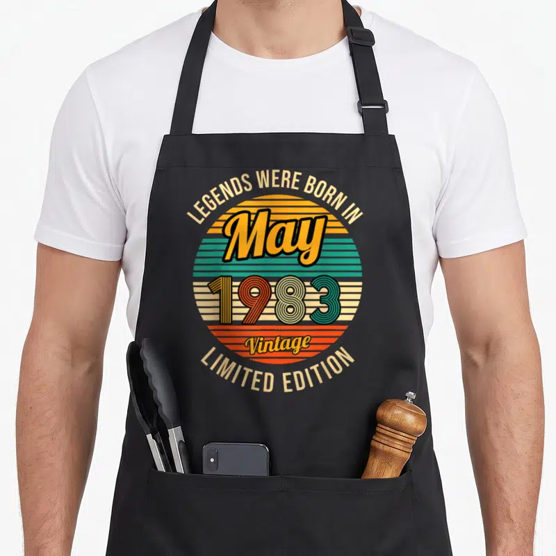 Tablier de cuisine noir avec motif circulaire retro affichant May 1983 et les mots Legends Were Born In Limited Edition Vintage.