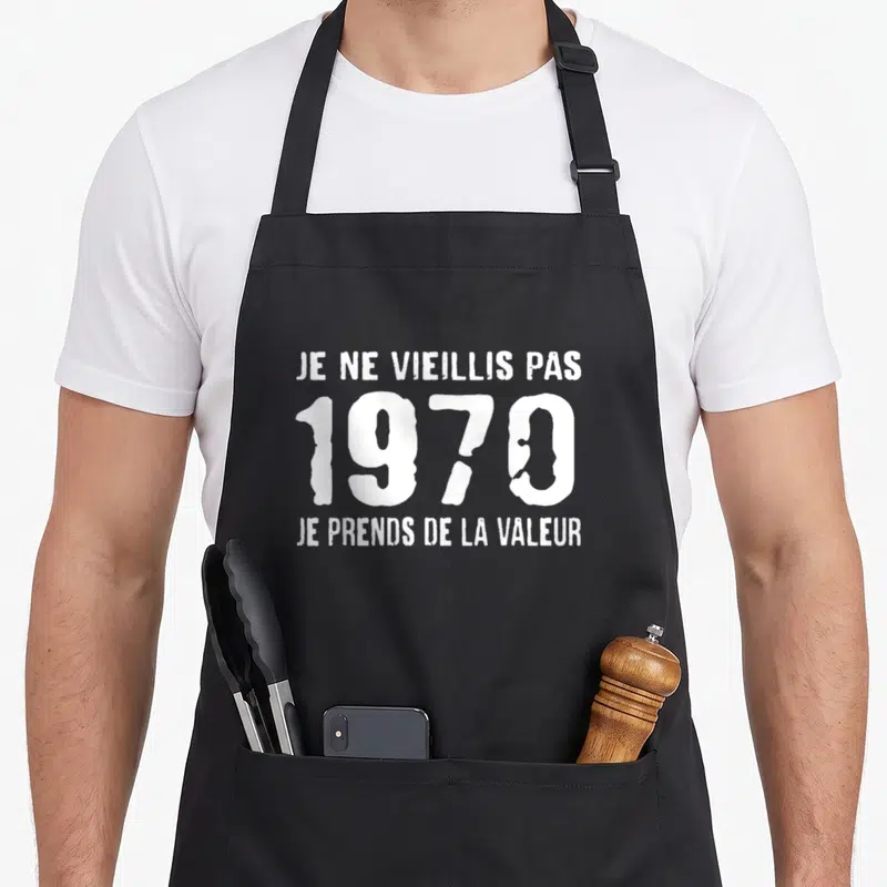 Tablier de cuisine noir avec inscription blanche Je ne vieillis pas 1970 je prends de la valeur en typographie stylisée.