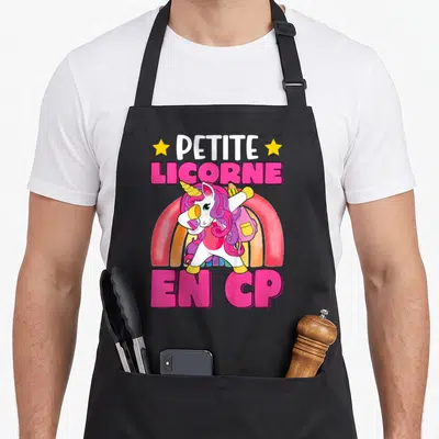 Tablier de cuisine noir avec licorne en CP, arc-en-ciel et texte rose vif.