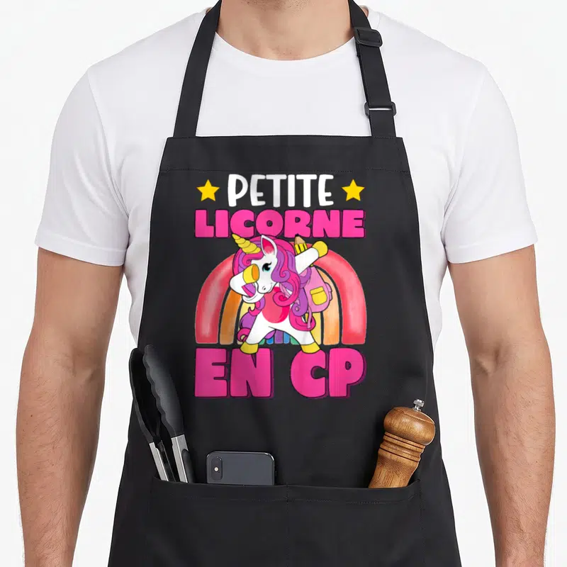 Tablier de cuisine noir avec licorne en CP, arc-en-ciel et texte rose vif.