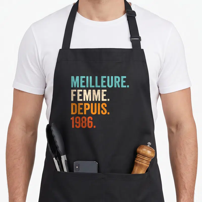 Tablier de cuisine noir avec inscription Meilleure Femme Depuis 1986 en lettres colorées style vintage.