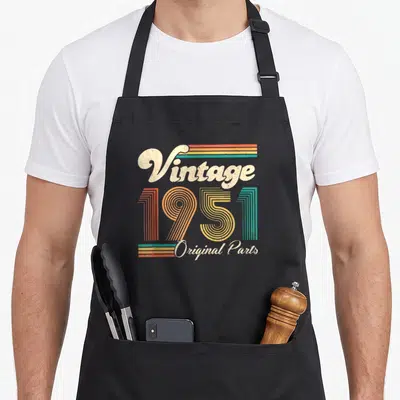 Tablier de cuisine noir avec motif vintage 1951 Original Parts en couleurs pastels et lettrage rétro.