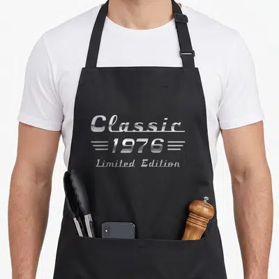 Tablier de cuisine noir avec l'inscription Classic 1976 Limited Edition en lettres argentées métallisées style chrome.