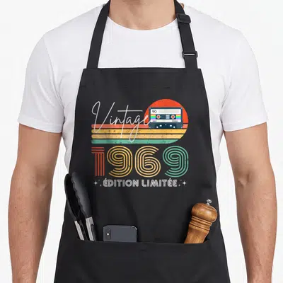 Tablier de cuisine noir avec illustration vintage 1969, cassette audio et soleil coloré rétro.