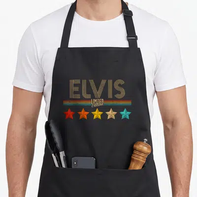 Tablier de cuisine noir avec inscription Elvis Limited Edition et cinq étoiles colorées alignées en bas.