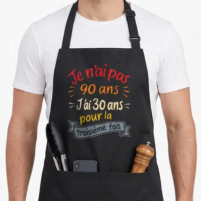 Tablier de cuisine noir avec inscription colorée Je n'ai pas 90 ans j'ai 30 ans pour la troisième fois sur fond gris uni.