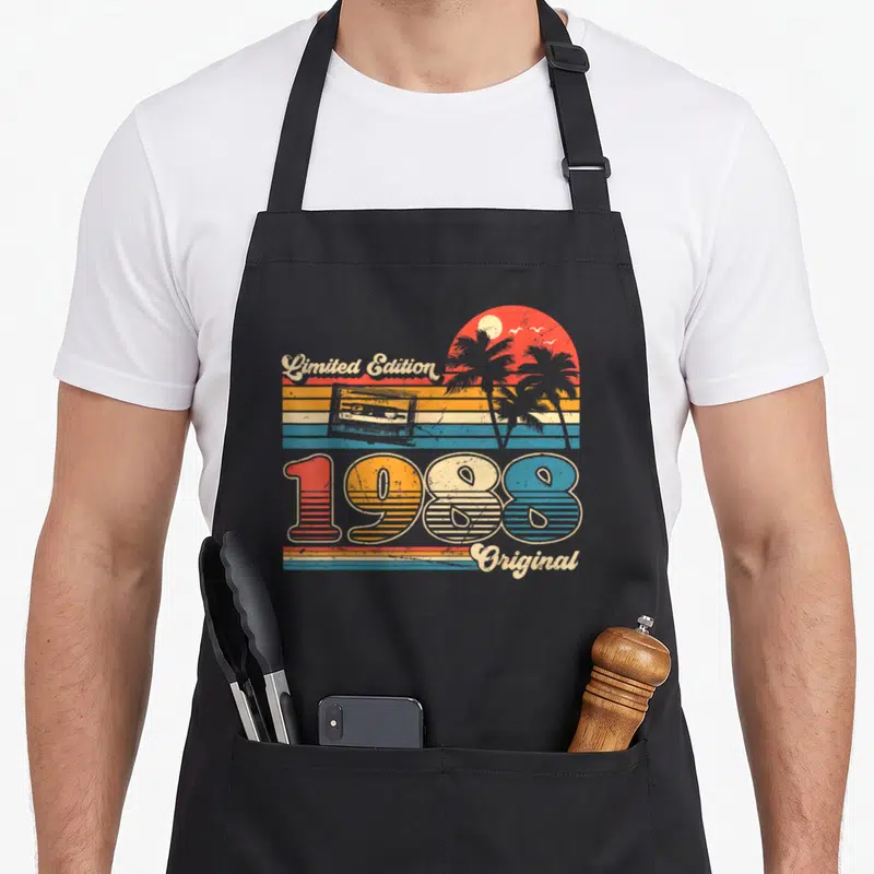 Tablier de cuisine noir avec motif vintage 1988, palmiers et cassette audio colorée.