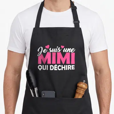 Tablier de cuisine noir avec le texte Je suis une Mimi qui déchire en blanc et rose.