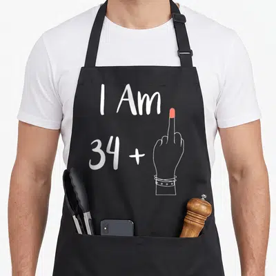 Tablier de cuisine noir avec l'inscription I Am 34 plus une main levant le majeur en rouge.