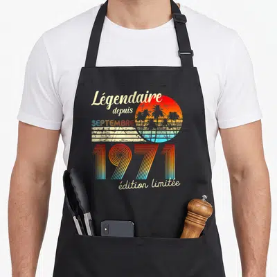 Tablier de cuisine noir avec motif rétro soleil couchant palmiers et texte Légendaire depuis septembre 1971