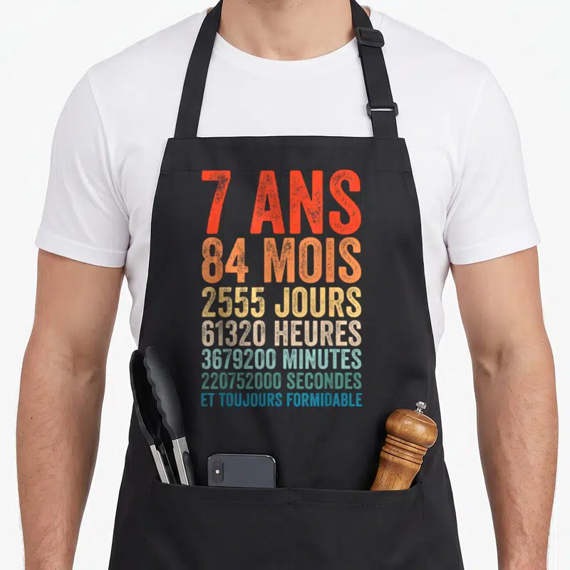 Tablier de cuisine noir avec typographie colorée indiquant sept ans et durées en mois jours heures minutes secondes.