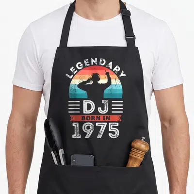 Tablier de cuisine noir avec silhouette DJ légendaire né en 1975 sur fond de soleil arc-en-ciel vintage