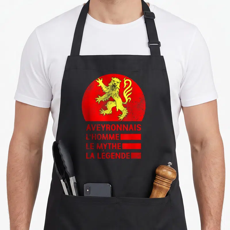 Tablier de cuisine noir avec un lion jaune stylisé sur fond rouge circulaire et du texte en rouge