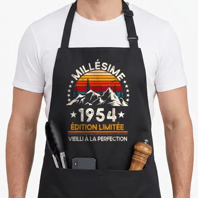 Tablier de cuisine noir avec illustration vintage Millésime 1954 Vieilli à la perfection sur fond de montagnes et soleil couchant.