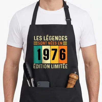 Tablier de cuisine noir avec inscription Les Légendes sont nées en 1976 sur bandes colorées vintage.