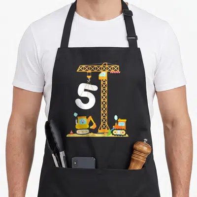Tablier de cuisine noir avec illustration de grue, pelleteuse, bulldozer et le chiffre 5 blanc sur fond de chantier.