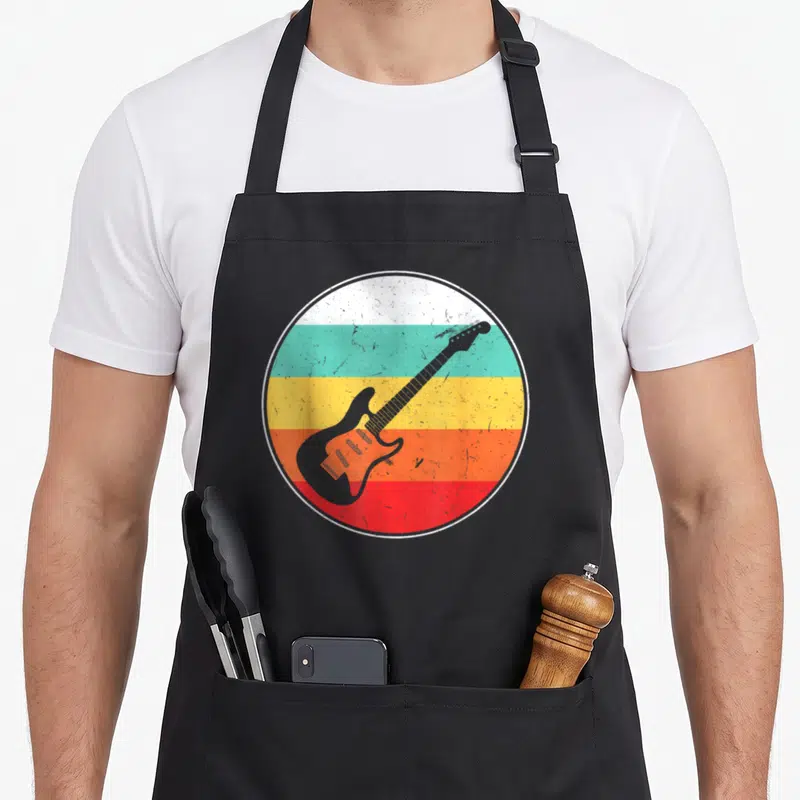 Tablier de cuisine noir avec un cercle affichant une guitare électrique sur des bandes horizontales multicolores et texturées.
