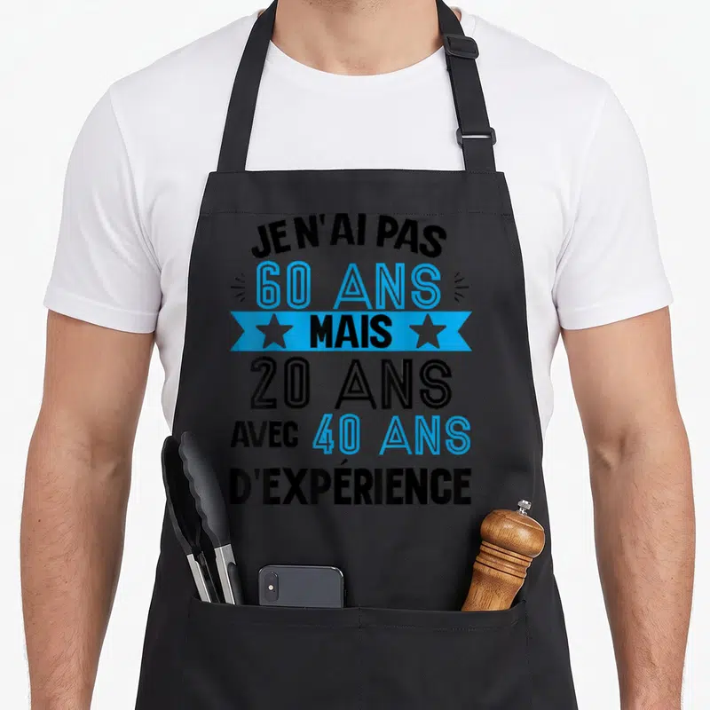 Tablier de cuisine noir avec le texte Je n'ai pas 60 ans mais 20 ans avec 40 ans d'expérience en bleu et noir.