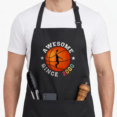 Tablier de cuisine noir avec balle de basket orange et silhouette de joueur en action entourée d'étoiles blanches.
