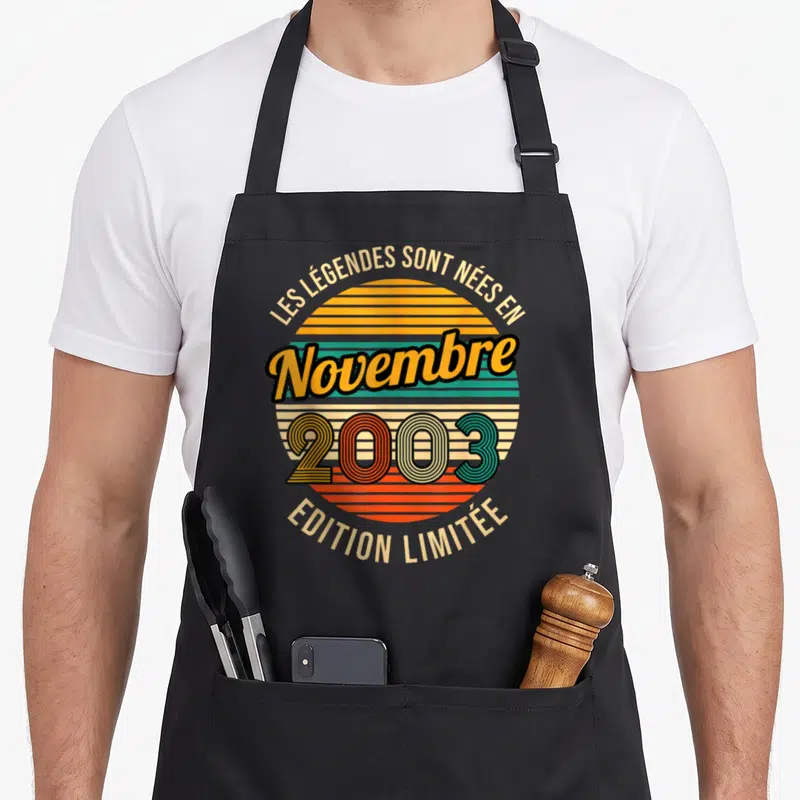 Tablier de cuisine noir avec motif circulaire retro affichant les mots Novembre 2003 et « Édition Limitée » sur fond de soleil stylisé.