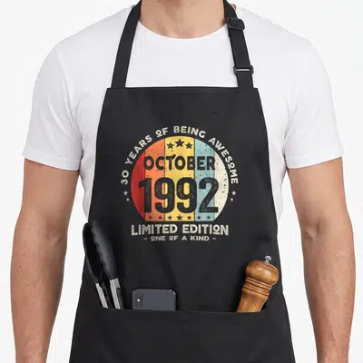Tablier de cuisine noir avec motif circulaire vintage affichant « 30 Years of Being Awesome » et l'année 1992 en couleurs dégradées.