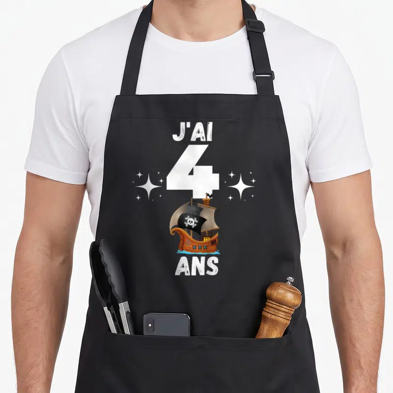 Tablier de cuisine noir avec un navire pirate, le chiffre 4 et les mots J'ai 4 ans entourés d'étoiles.