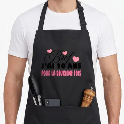 Tablier de cuisine noir avec inscription « Bref j'ai 20 ans pour la deuxième fois » et cœurs roses, design d'anniversaire.