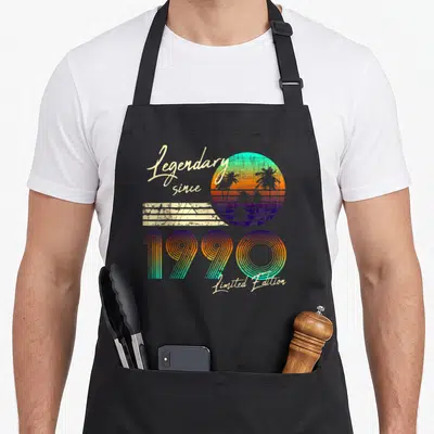 Tablier de cuisine noir avec illustration rétro 1990 et soleil couchant aux palmiers.