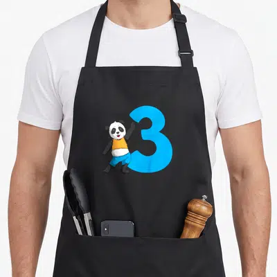 Tablier de cuisine noir avec illustration d'un ours panda portant un « t-shirt » orange et le chiffre 3 bleu vif.
