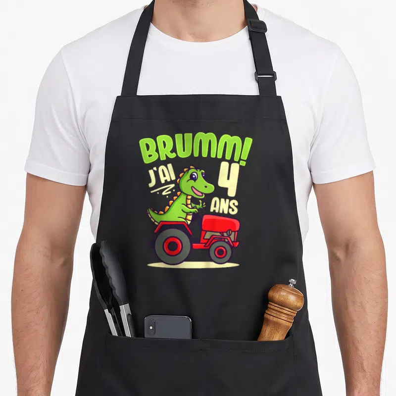 Tablier de cuisine noir avec dinosaure vert sur tracteur rouge et texte J'ai 4 ans Brumm.
