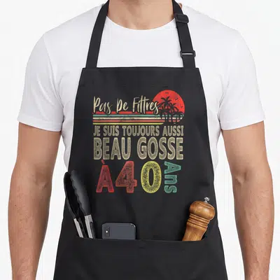Tablier de cuisine noir avec inscription retro Je suis toujours aussi beau gosse à 40 ans et illustration de soleil couchant.