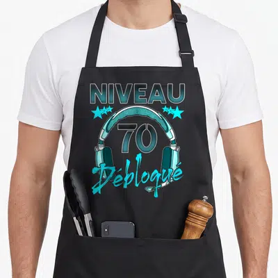 Tablier de cuisine noir avec casque audio bleu et texte Niveau 70 Débloqué imprimé au centre.