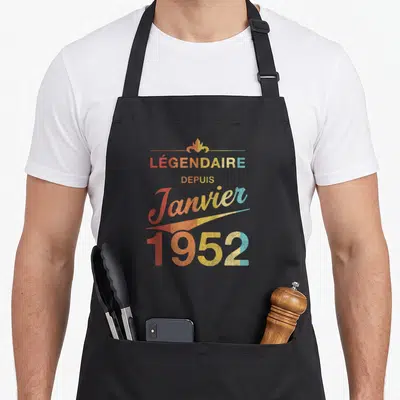 Tablier de cuisine noir avec inscription Légendaire depuis Janvier 1952 en typographie vintage multicolore.